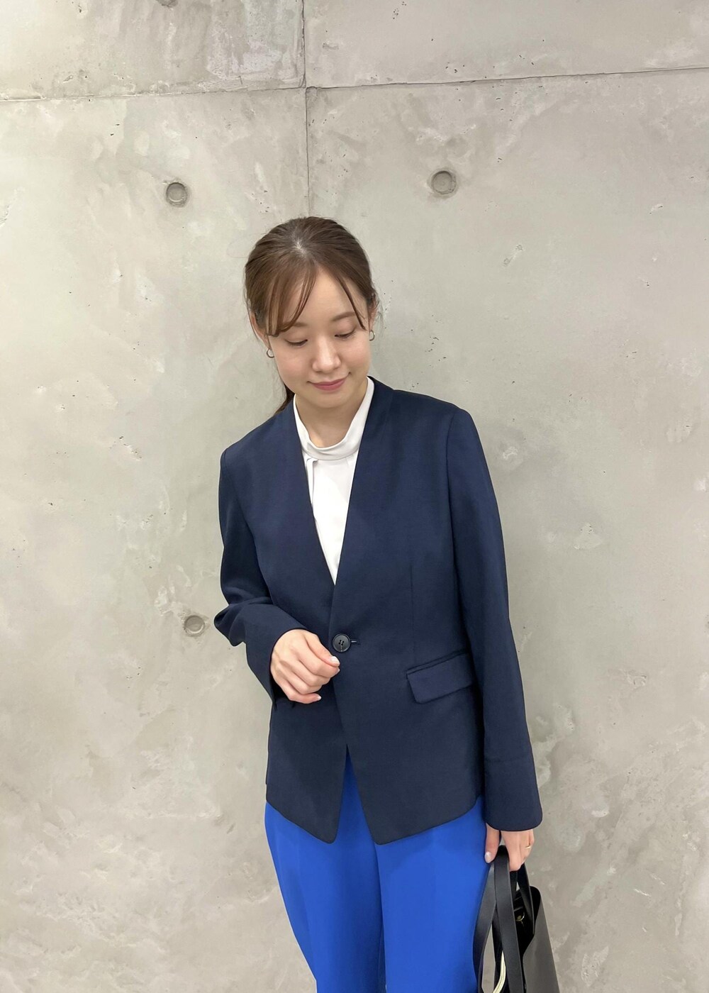 ブラック系のパンプス、ブルー系のスラックス、ブラック系のトートバッグを着用したレディースの春コーディネートの8枚目の写真