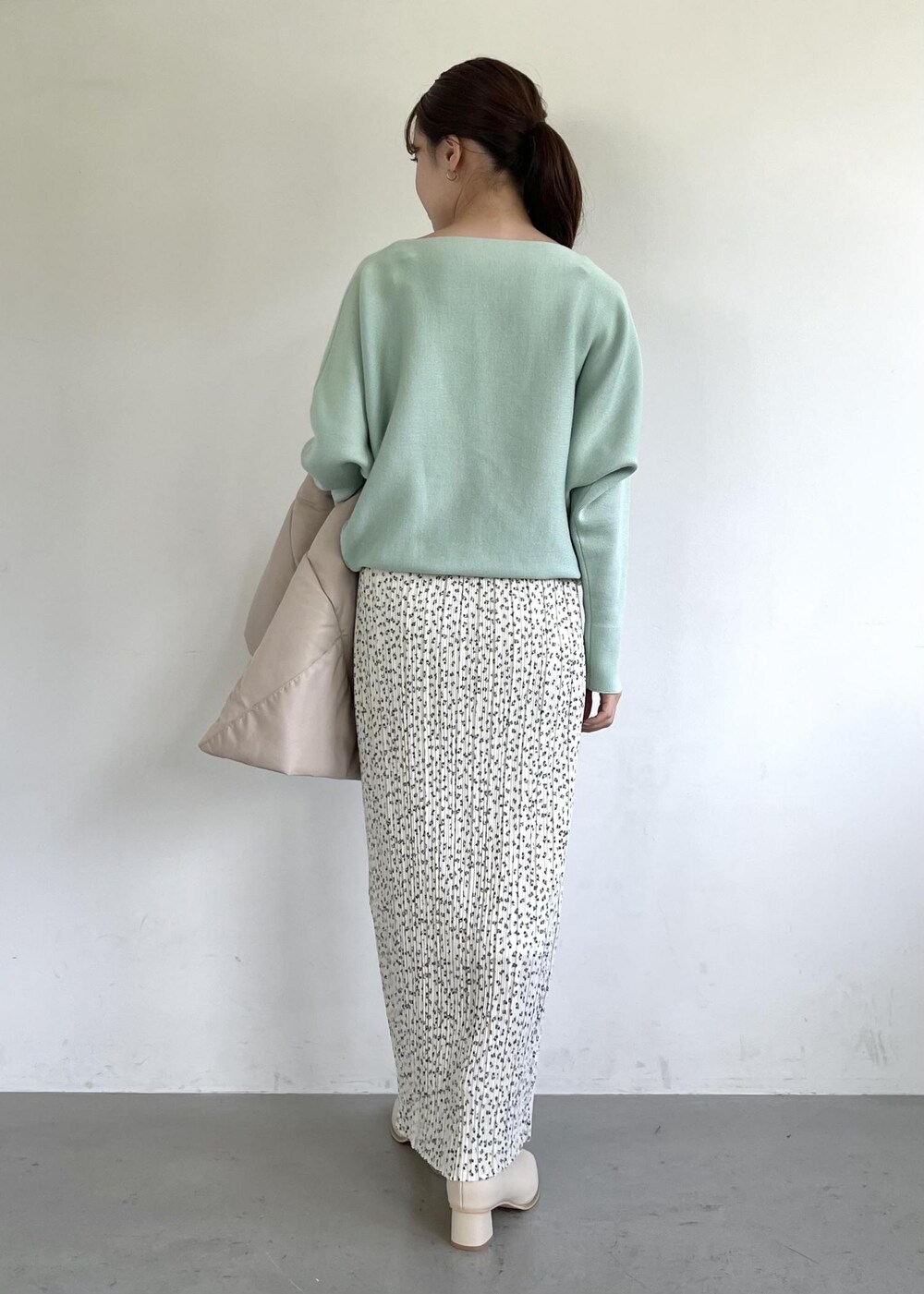 グリーン系のニット/セーター、ホワイト系のブーツ、ホワイト系のスカートを着用したレディースの秋コーディネートの6枚目の写真