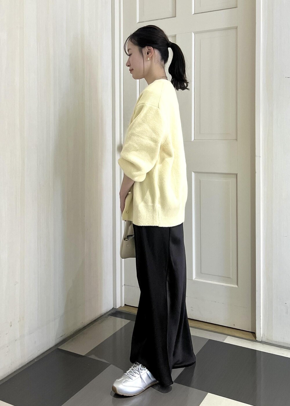 ホワイト系のショルダーバッグ、シルバー系のスニーカー、ベージュ系のカーディガン/ボレロを着用したレディースの冬コーディネートの3枚目の写真