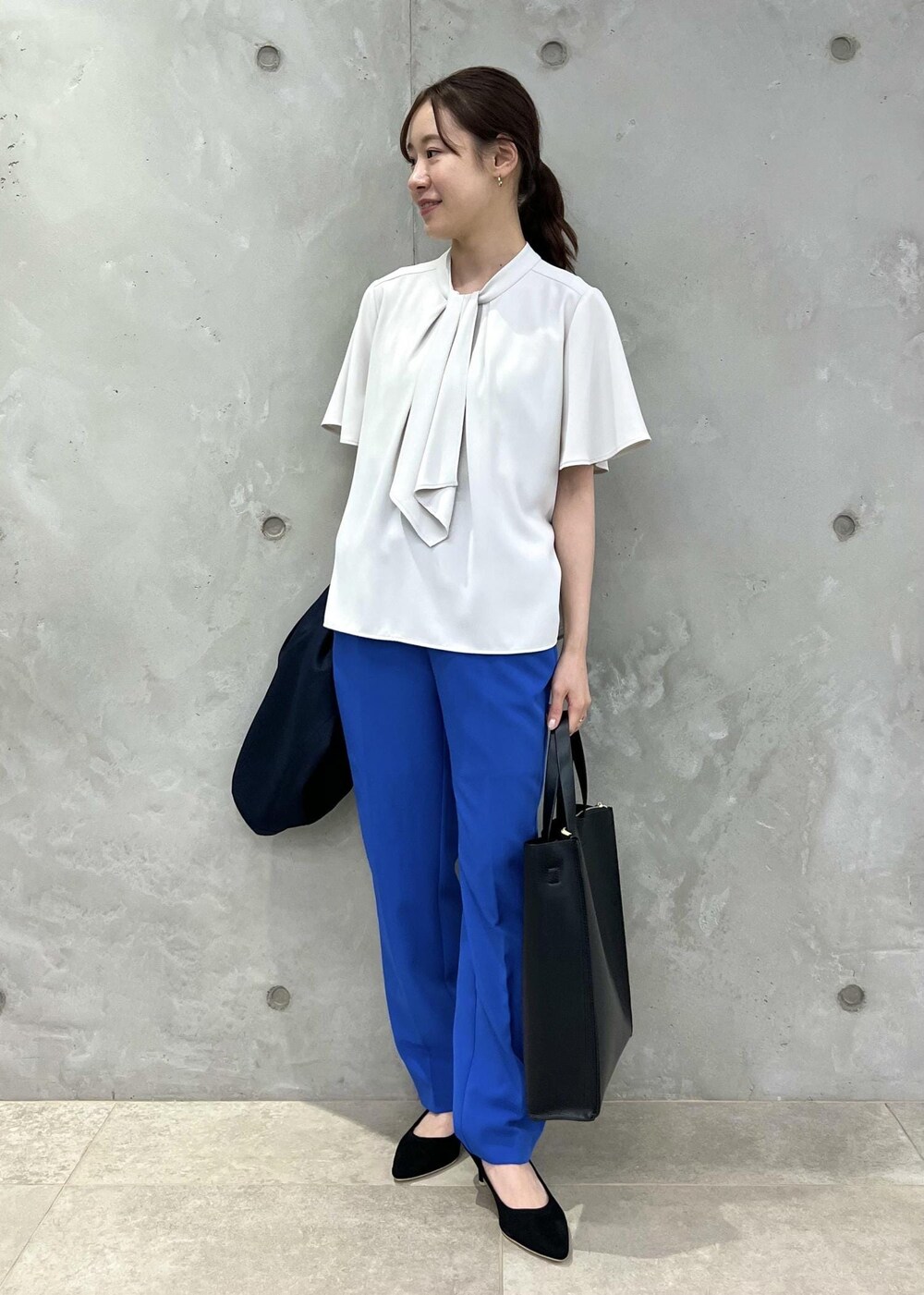 ブラック系のパンプス、ブルー系のスラックス、ブラック系のトートバッグを着用したレディースの春コーディネートの4枚目の写真