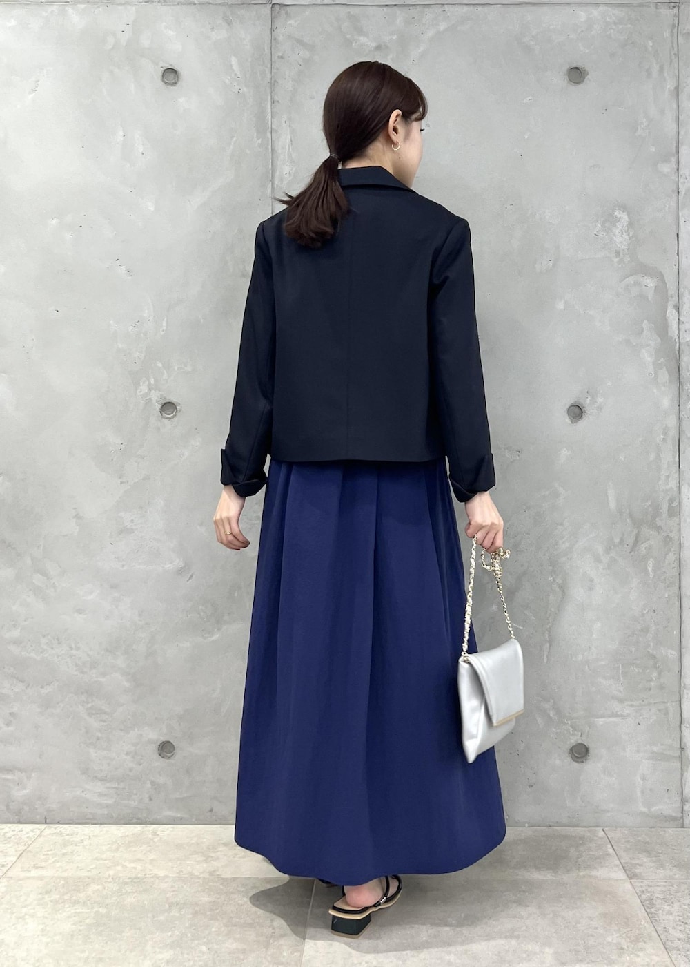 ブルー系のテーラードジャケット、ブラック系のサンダル、ブルー系のワンピースを着用したレディースの夏コーディネートの3枚目の写真