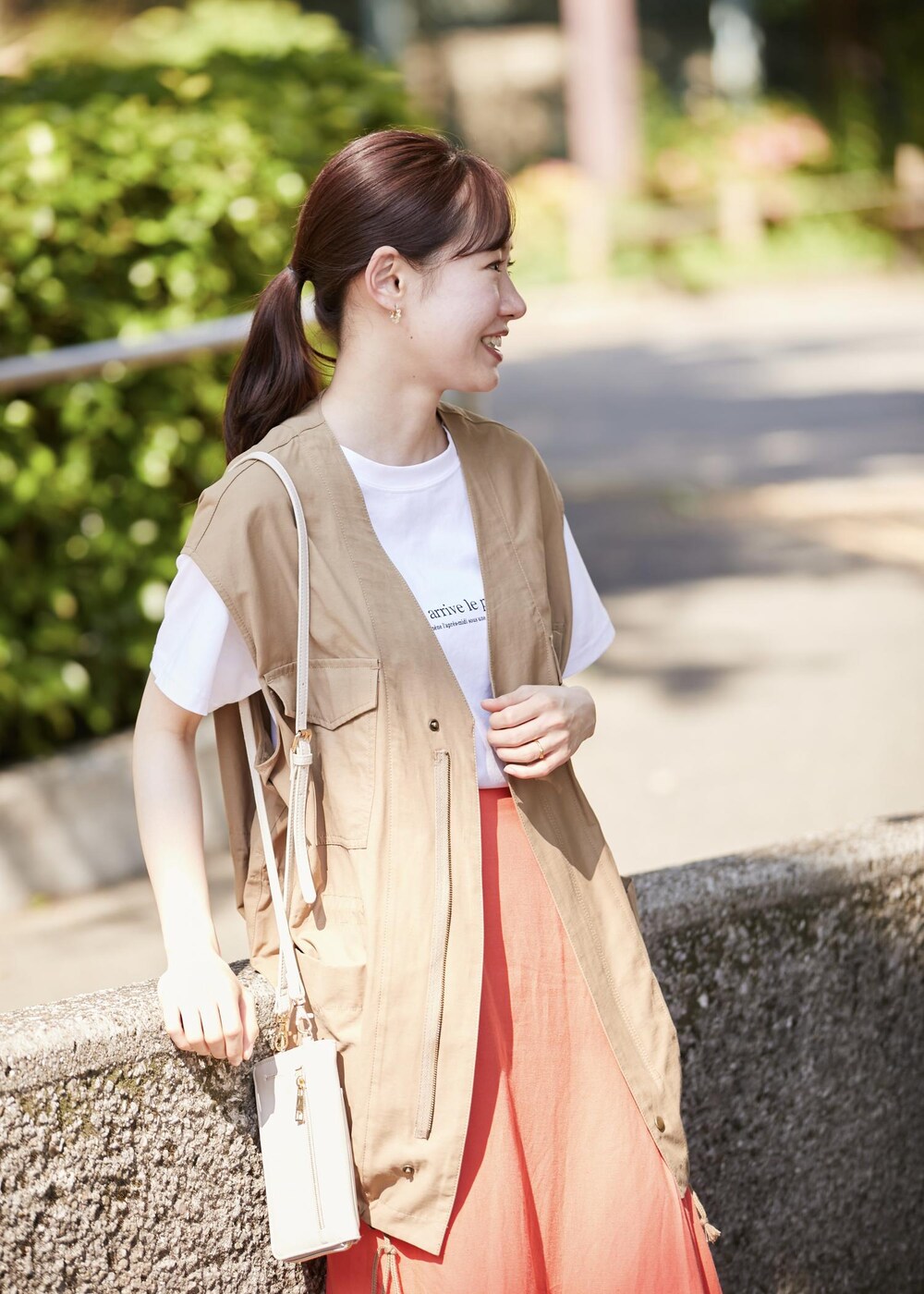 イエロー系のベスト、ホワイト系のショルダーバッグ、ホワイト系のTシャツ/カットソーを着用したレディースの春コーディネートの2枚目の写真