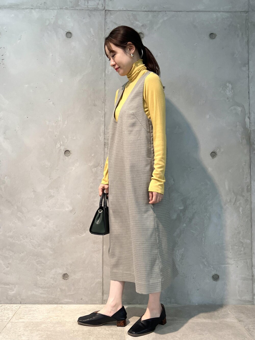 グリーン系のジャンパースカート、ブラック系のショルダーバッグ、ブラック系のその他シューズを着用したレディースの夏コーディネートの2枚目の写真