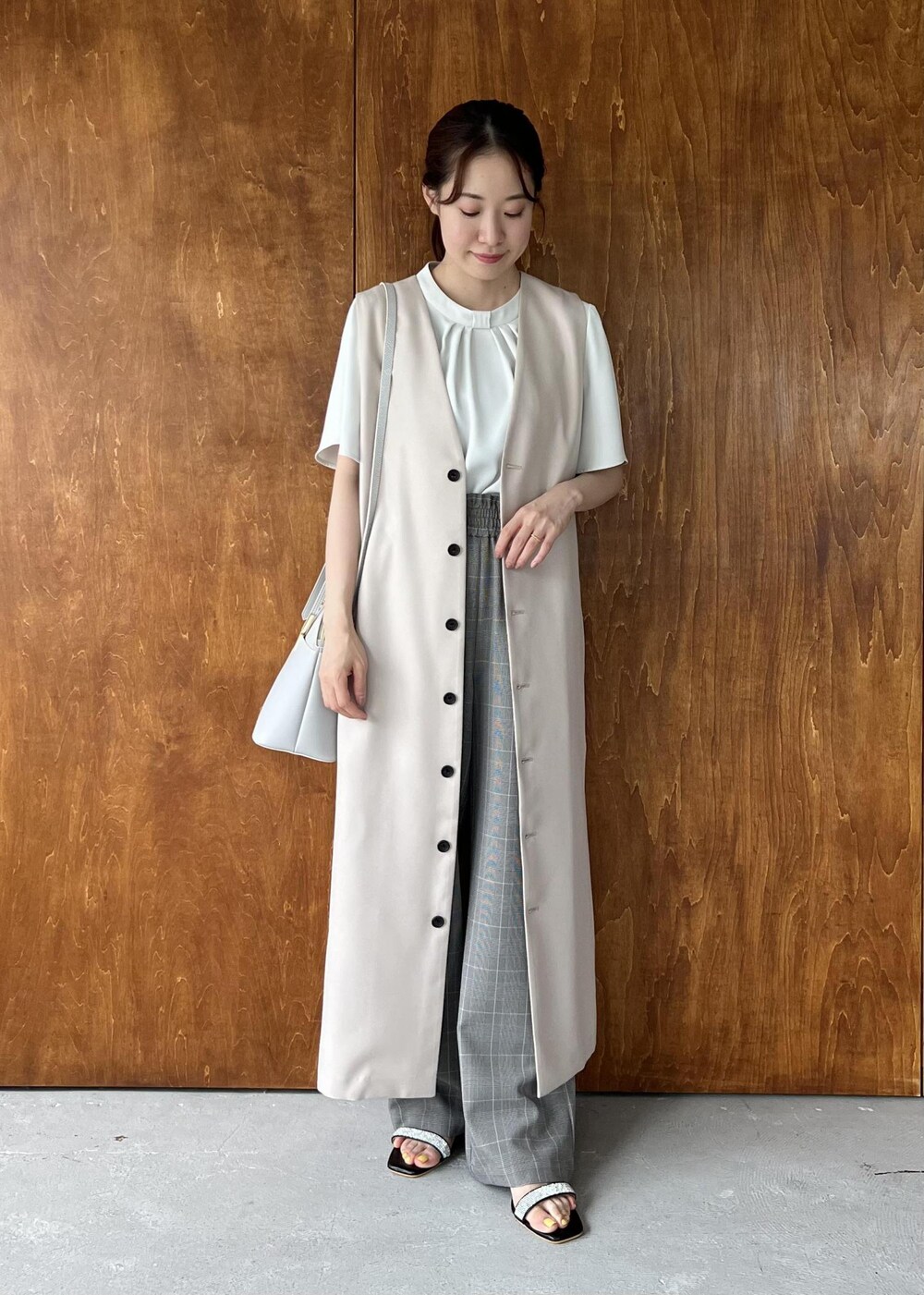 ブラック系のサンダル、ベージュ系のジャンパースカート、ホワイト系のシャツ/ブラウスを着用したレディースの夏コーディネートの4枚目の写真