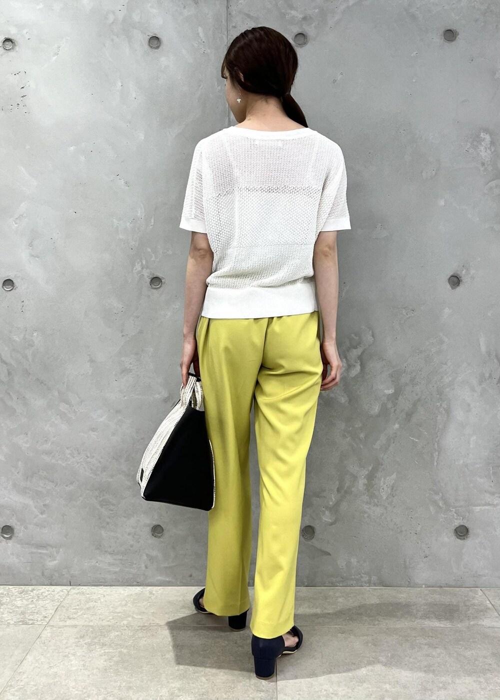 ブラック系のサンダル、イエロー系のスラックス、ブラック系のショルダーバッグを着用したレディースの夏コーディネートの3枚目の写真