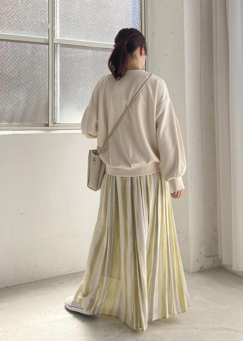 イエロー系のスカート、ホワイト系のニット/セーターを着用したレディースの夏コーディネートの2枚目の写真