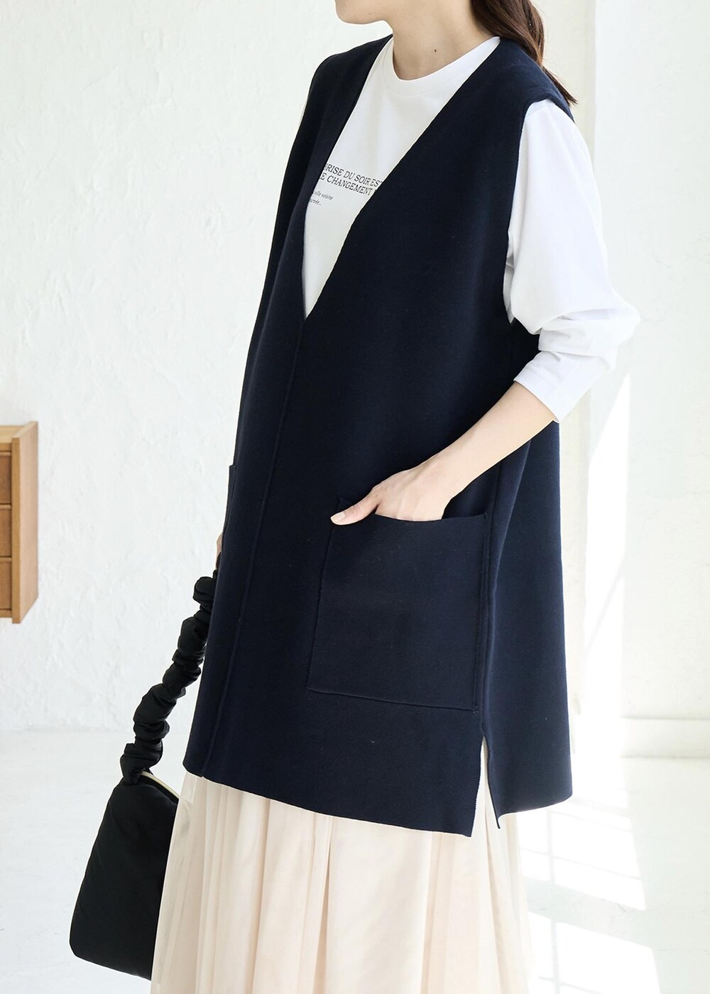 ベージュ系のスカート、ホワイト系のパンプス、ブルー系のベストを着用したレディースの秋コーディネートの3枚目の写真