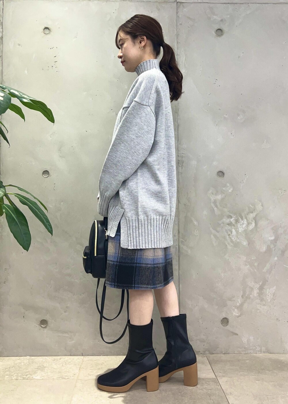 ブラック系のバックパック/リュック、グレー系のニット/セーター、ブラック系のブーツを着用したレディースの秋コーディネートの2枚目の写真