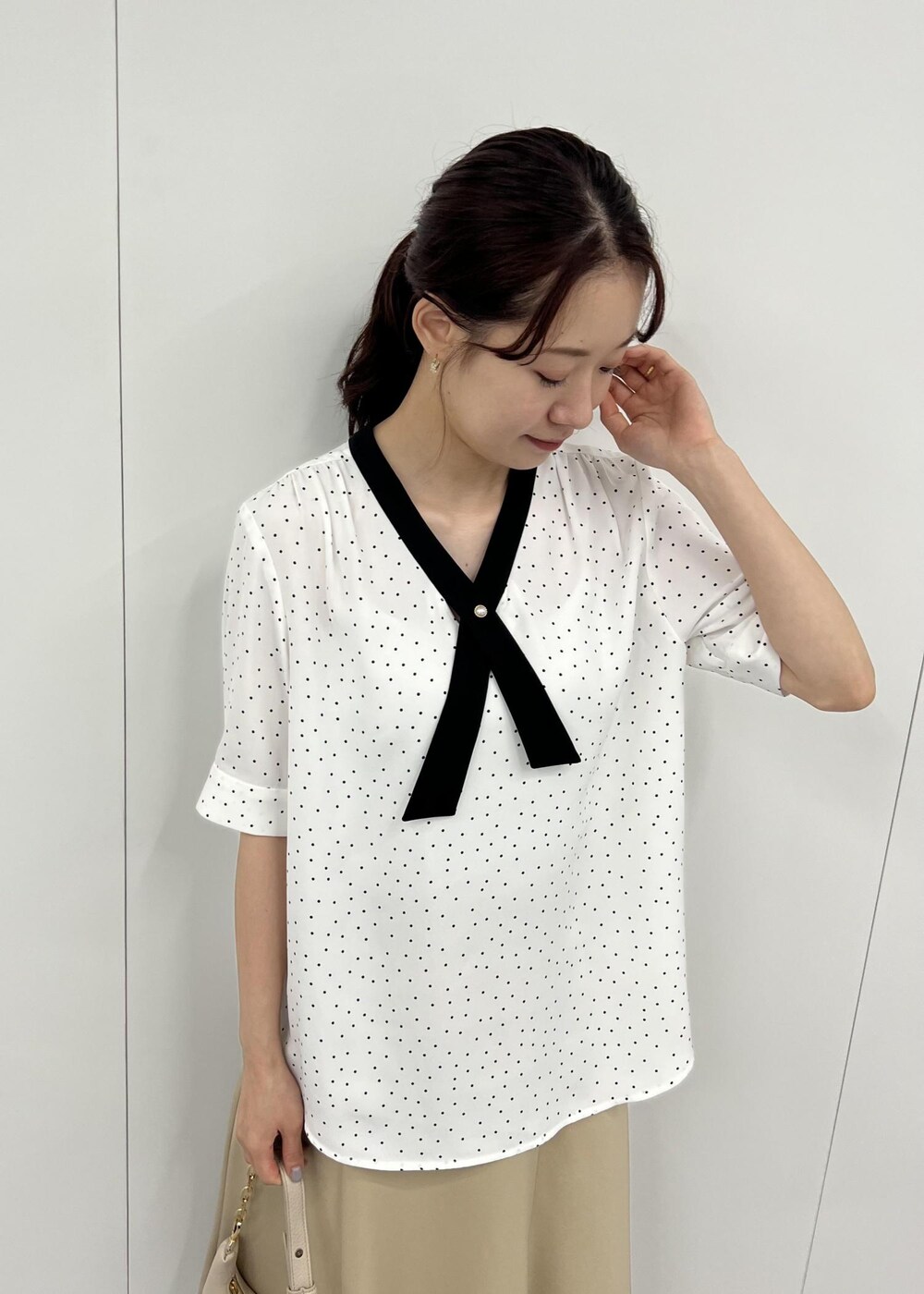 ベージュ系のショルダーバッグ、ベージュ系のスカート、ホワイト系のシャツ/ブラウスを着用したレディースの夏コーディネートの4枚目の写真