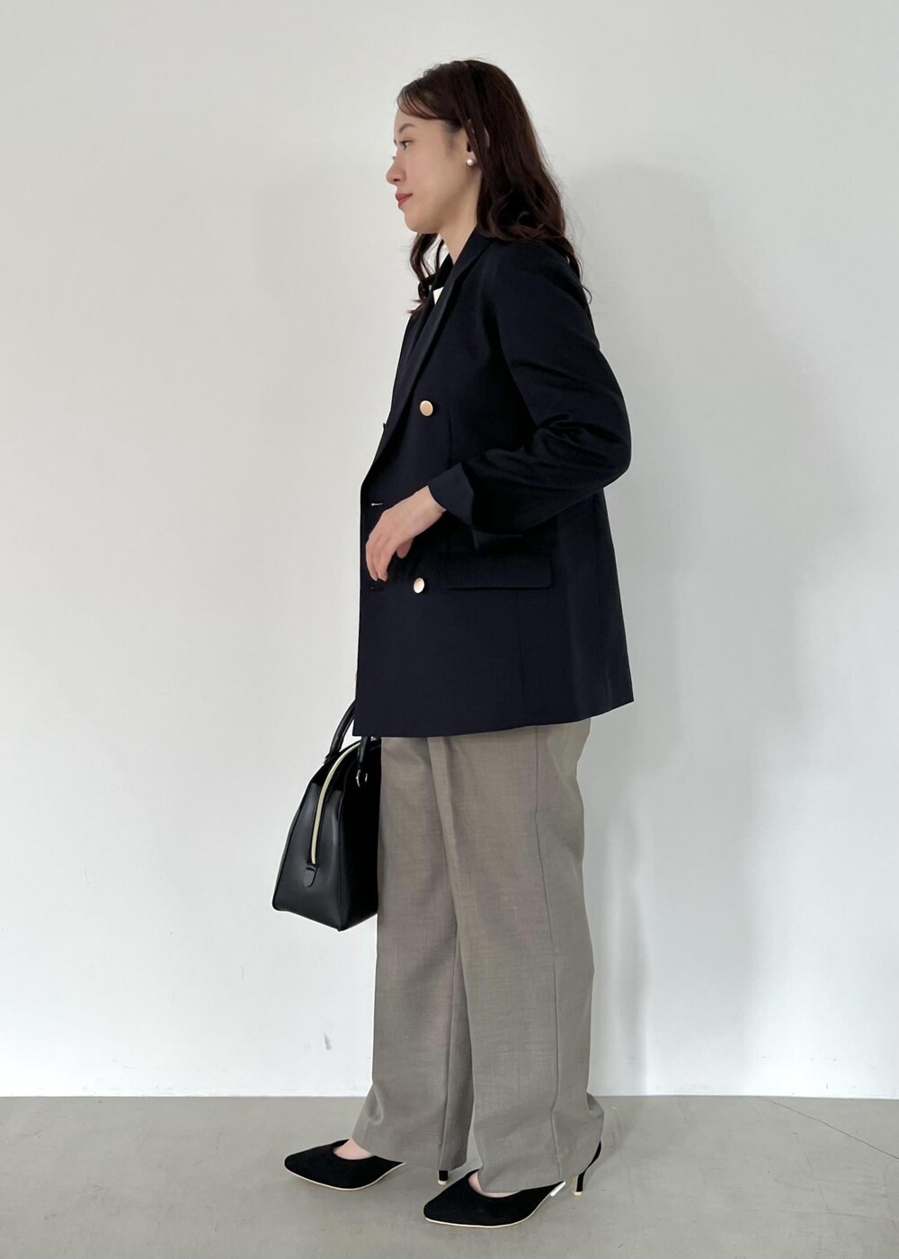 ブラック系のボストンバッグ、ブルー系のテーラードジャケット、ホワイト系のニット/セーターを着用したレディースの秋コーディネートの2枚目の写真