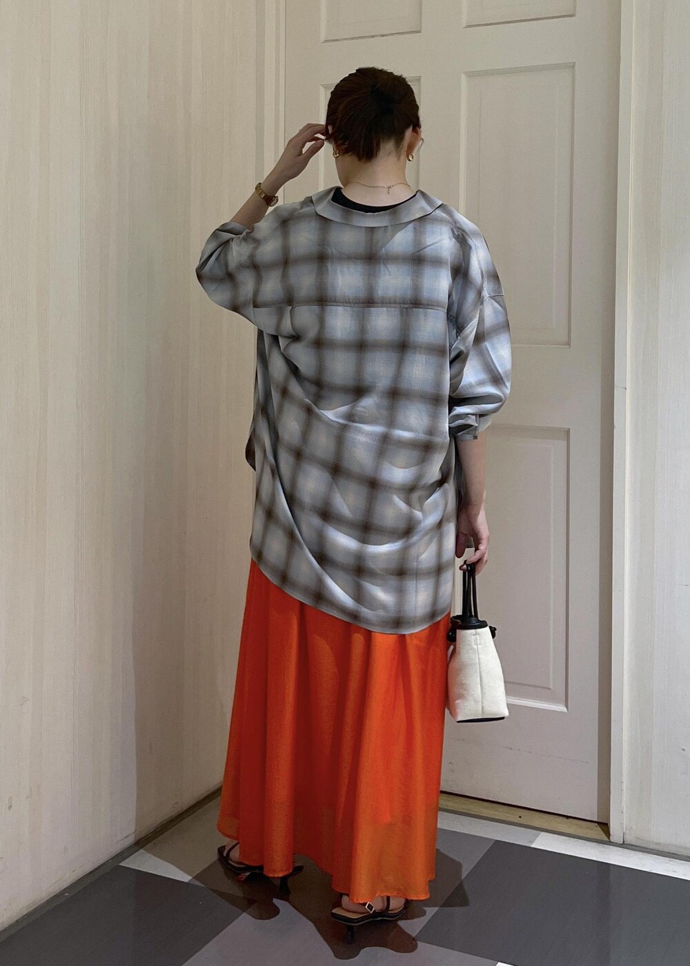 オレンジ系のスカート、ブラック系のタンクトップ、ブラック系のサンダルを着用したレディースの夏コーディネートの4枚目の写真