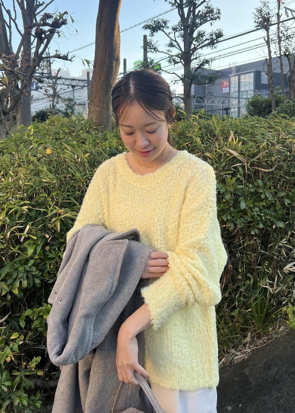 ベージュ系のチェスターコート、ブラウン系のショルダーバッグ、イエロー系のニット/セーターを着用したレディースの秋コーディネートの9枚目の写真