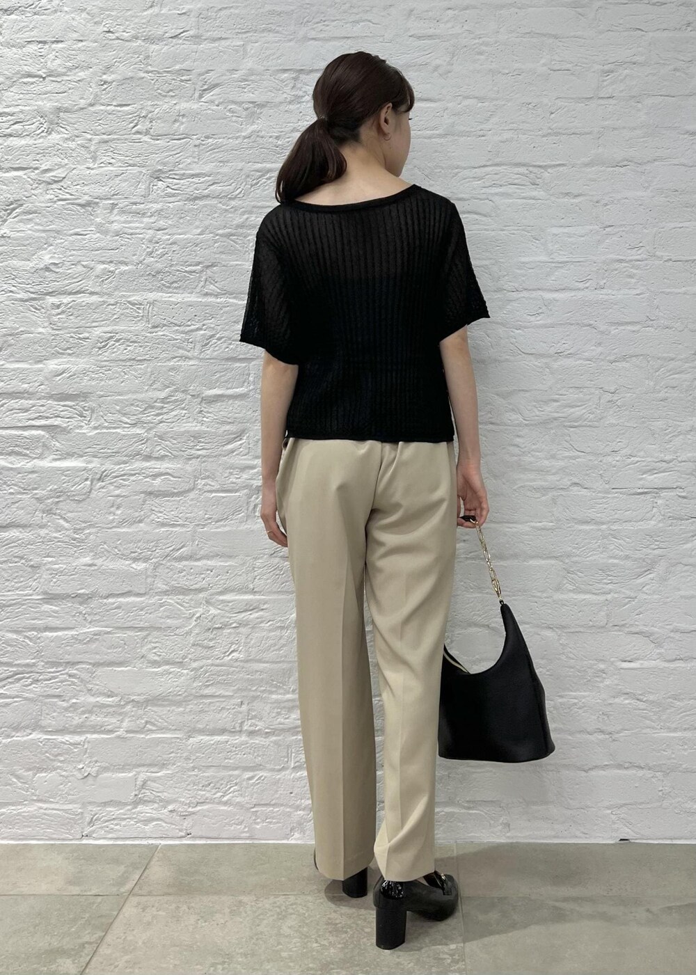 ブラック系のローファー、ブラック系のショルダーバッグ、ベージュ系のスラックスを着用したレディースの夏コーディネートの3枚目の写真