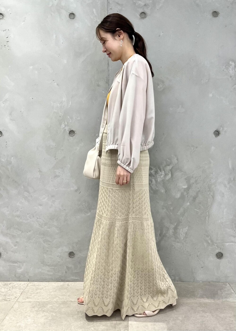 ベージュ系のサンダル、ベージュ系のブルゾン、オレンジ系のニット/セーターを着用したレディースの春コーディネートの2枚目の写真