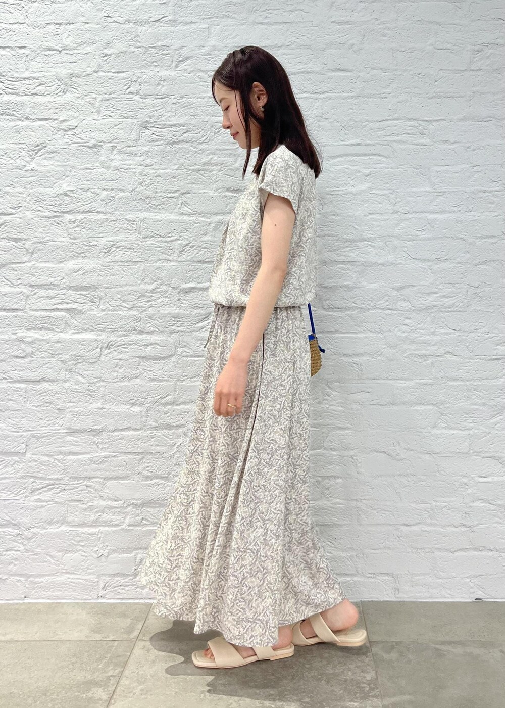 ブルー系のショルダーバッグ、ベージュ系のワンピース、ホワイト系のサンダルを着用したレディースの夏コーディネートの2枚目の写真