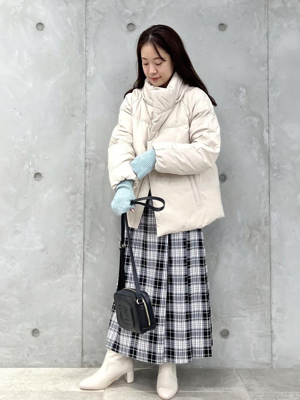 ホワイト系のダウンジャケット/コート、ホワイト系のスカート、ブラック系のショルダーバッグを着用したレディースの冬コーディネートの2枚目の写真