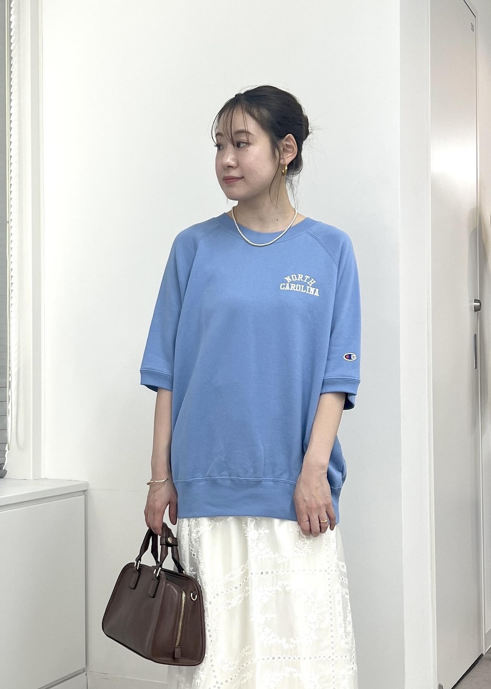 ブラウン系のボストンバッグ、ベージュ系のパンプス、ホワイト系のスカートを着用したレディースの夏コーディネートの8枚目の写真