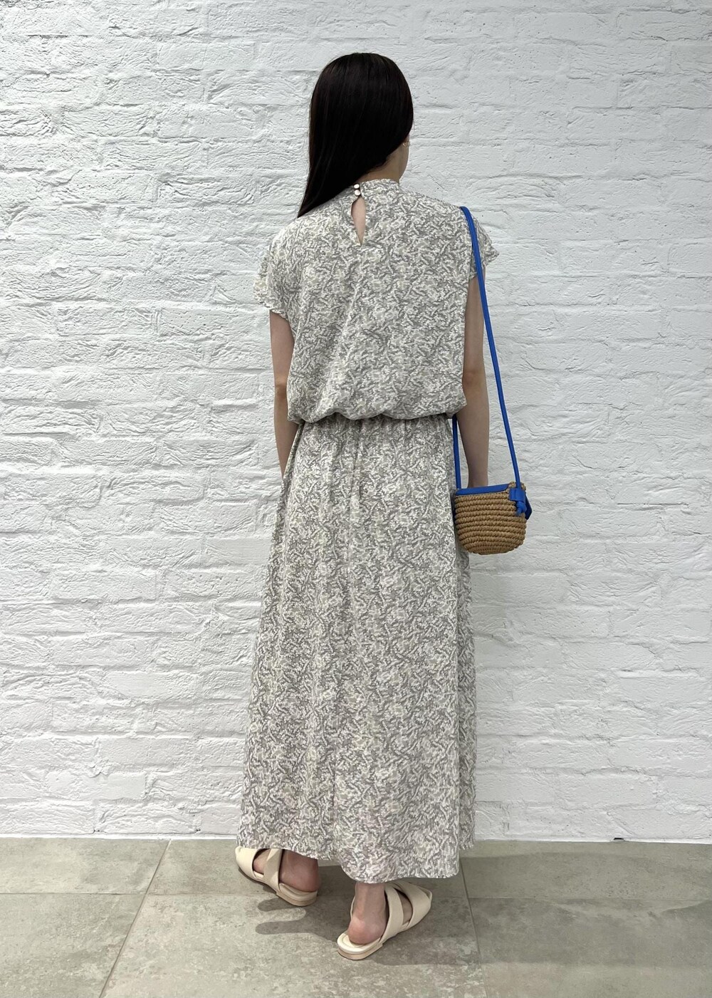 ブルー系のショルダーバッグ、ベージュ系のワンピース、ホワイト系のサンダルを着用したレディースの夏コーディネートの3枚目の写真