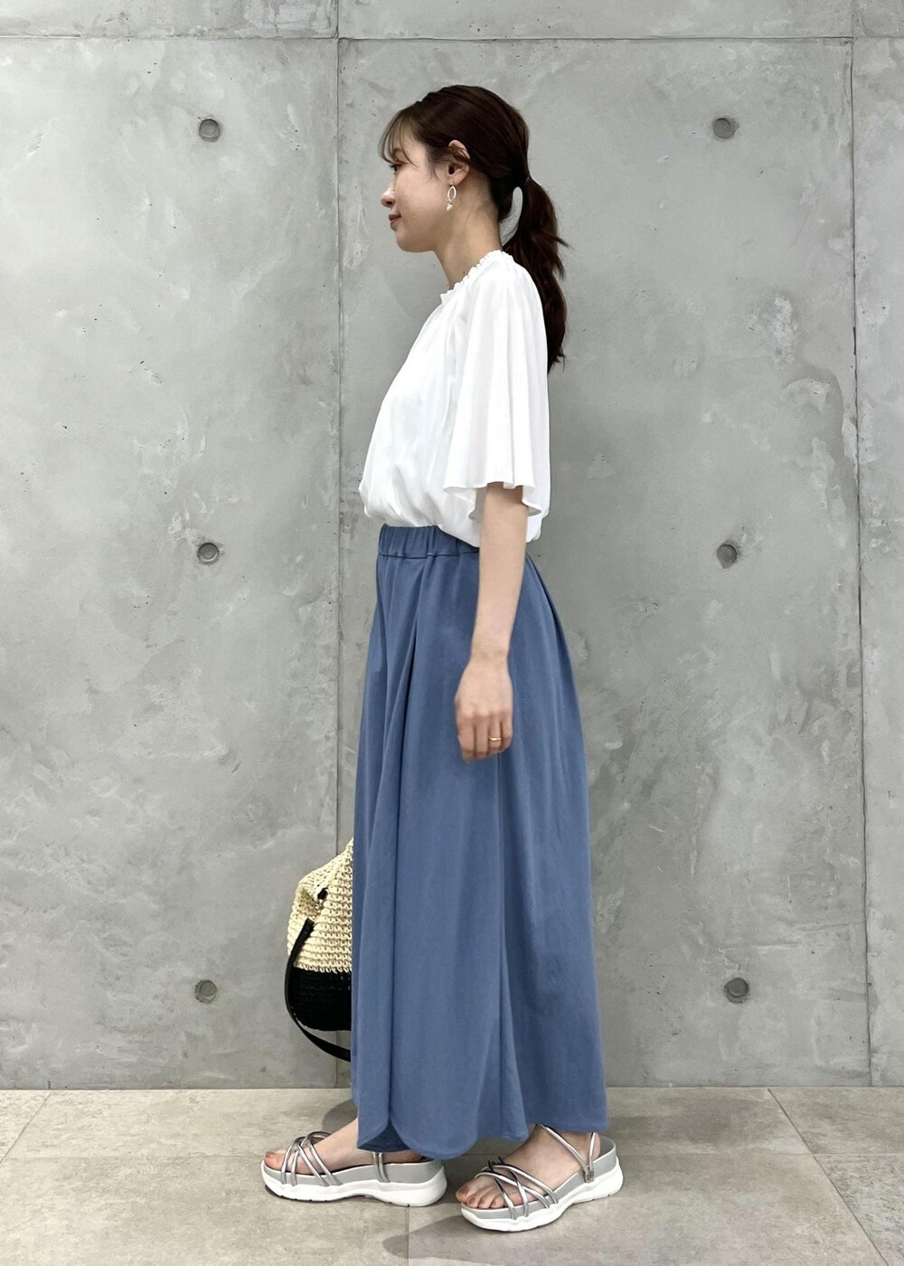 ブラック系のトートバッグ、シルバー系のサンダル、ホワイト系のシャツ/ブラウスを着用したレディースの夏コーディネートの2枚目の写真