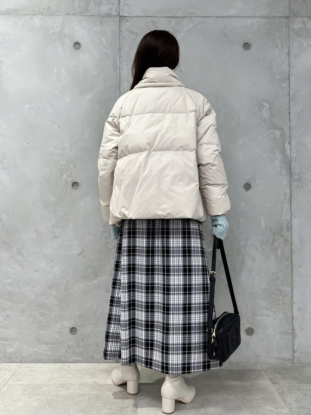 ホワイト系のダウンジャケット/コート、ホワイト系のスカート、ブラック系のショルダーバッグを着用したレディースの冬コーディネートの4枚目の写真