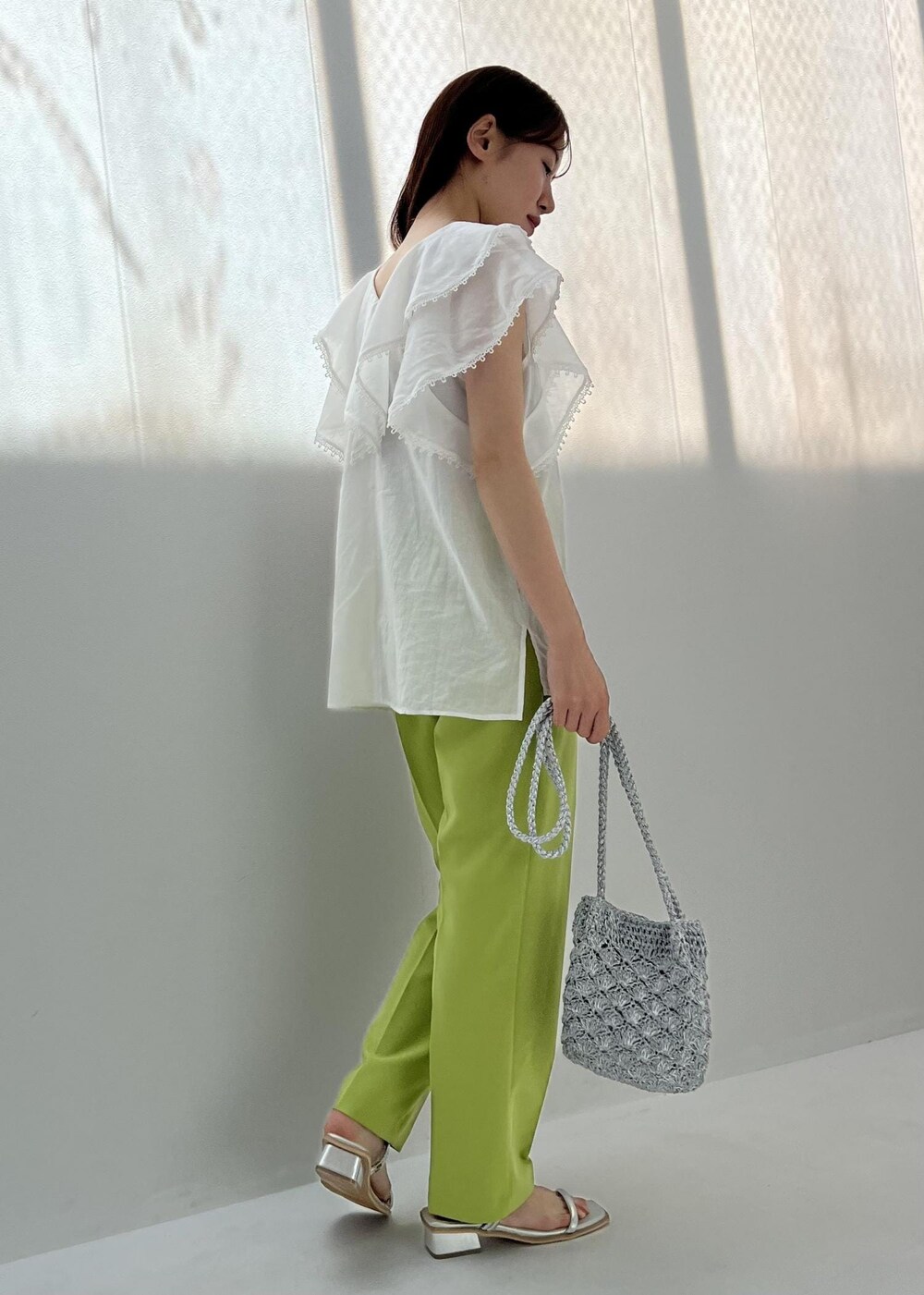 グリーン系のスラックス、シルバー系のショルダーバッグ、シルバー系のサンダルを着用したレディースの夏コーディネートの2枚目の写真