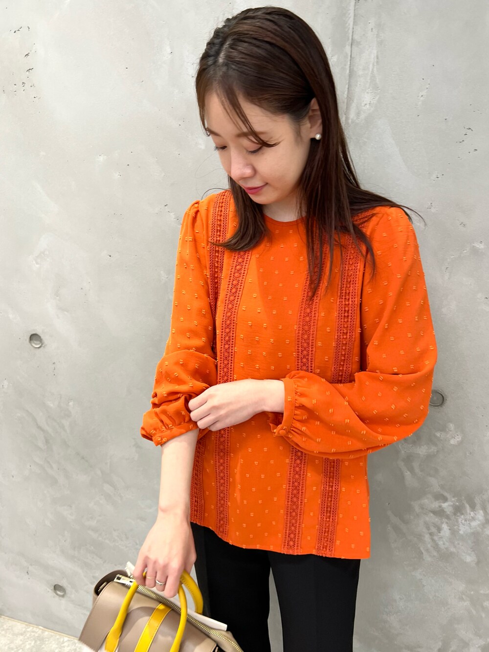 オレンジ系のシャツ/ブラウス、イエロー系のショルダーバッグ、ブラック系のその他パンツを着用したレディースの春コーディネートの3枚目の写真