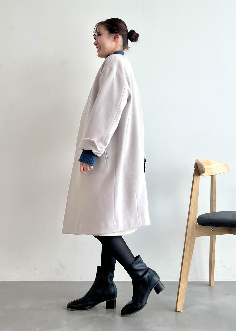 ブルー系のニット/セーター、ブラック系のブーツ、グレー系のノーカラーコートを着用したレディースの冬コーディネートの2枚目の写真