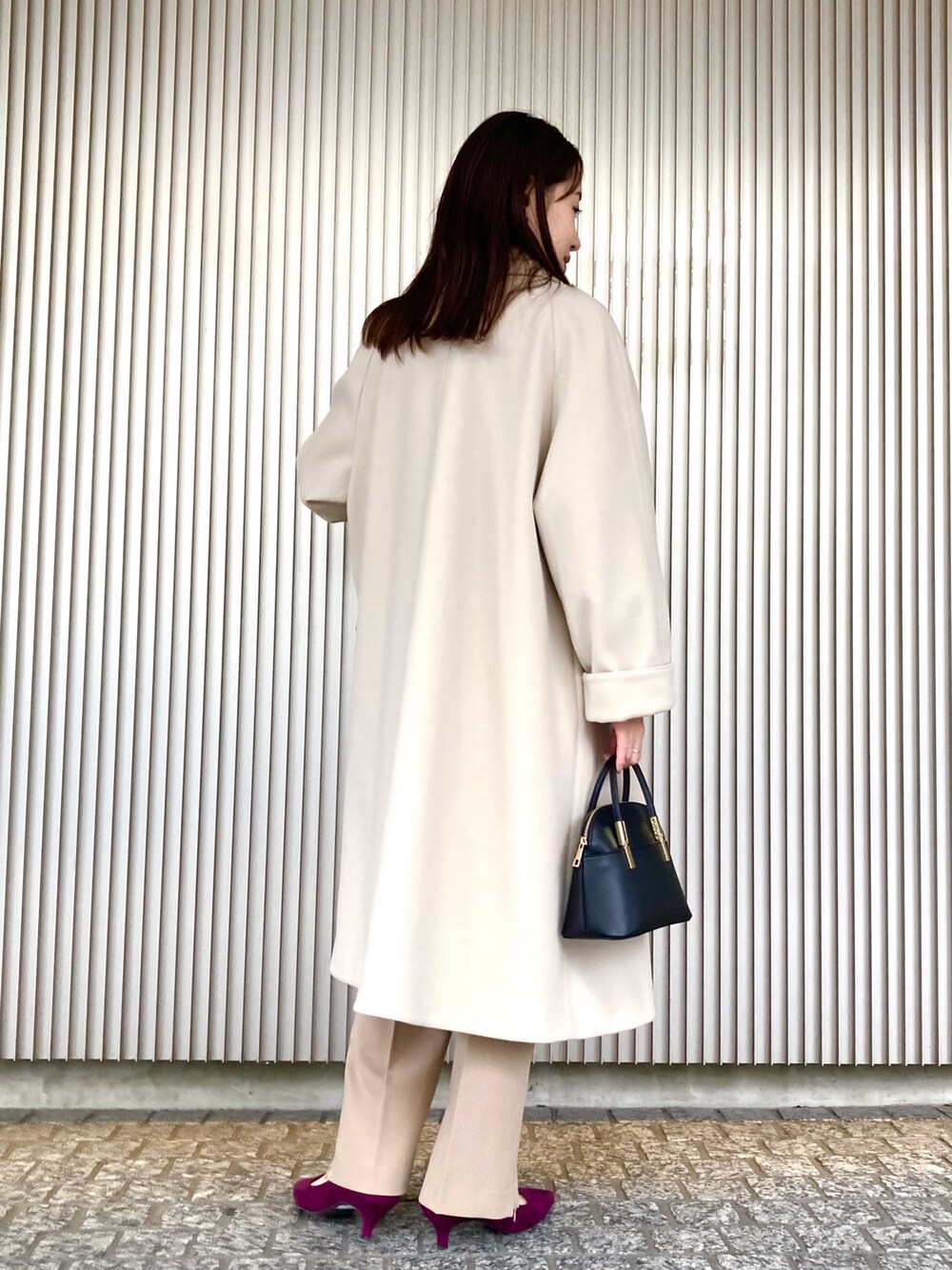 ブラック系のニット/セーター、ベージュ系のステンカラーコート、ブラック系のショルダーバッグを着用したレディースの秋コーディネートの3枚目の写真
