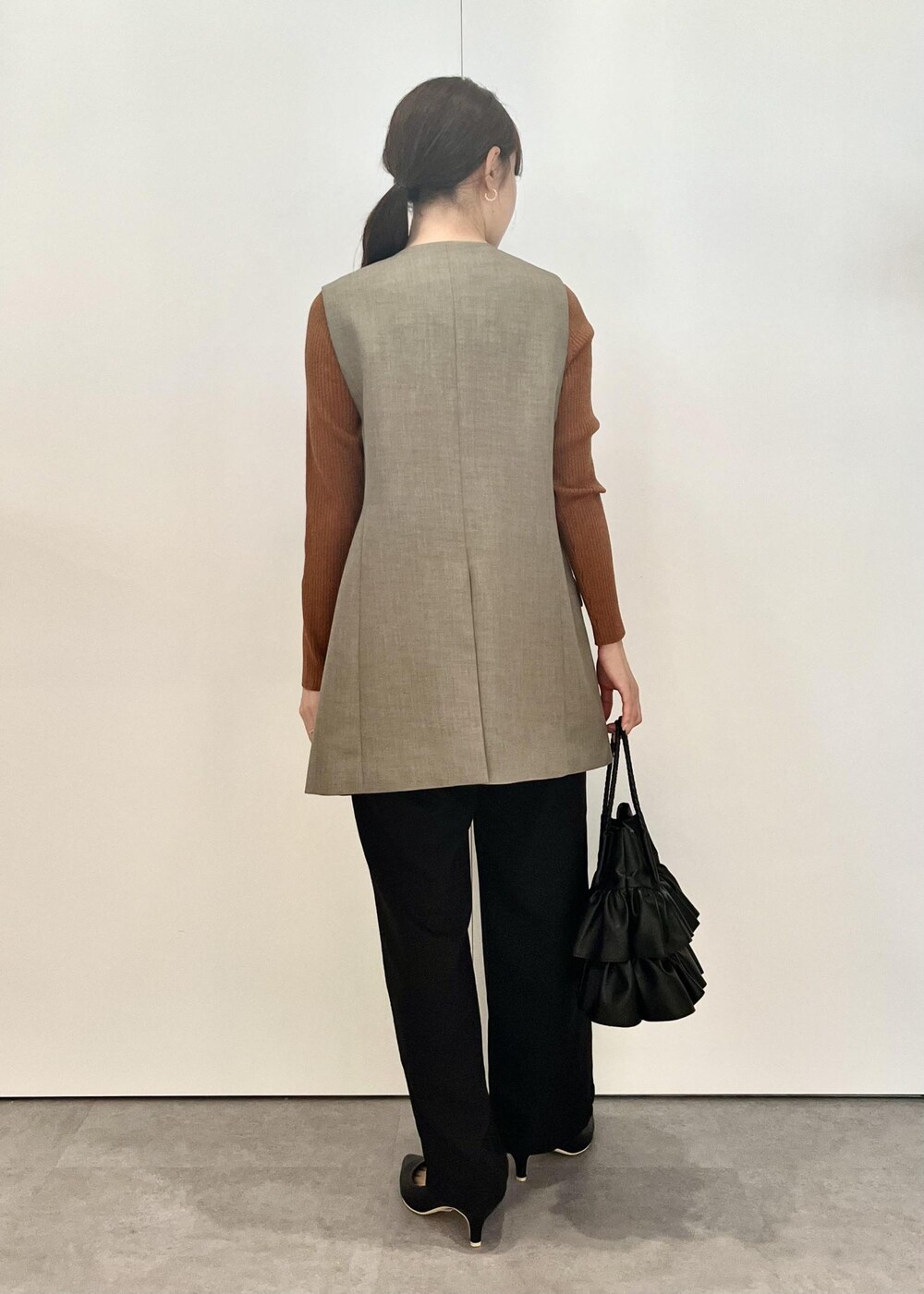 ブラック系のトートバッグ、ブラック系のその他パンツ、ブラウン系のカーディガン/ボレロを着用したレディースの秋コーディネートの3枚目の写真