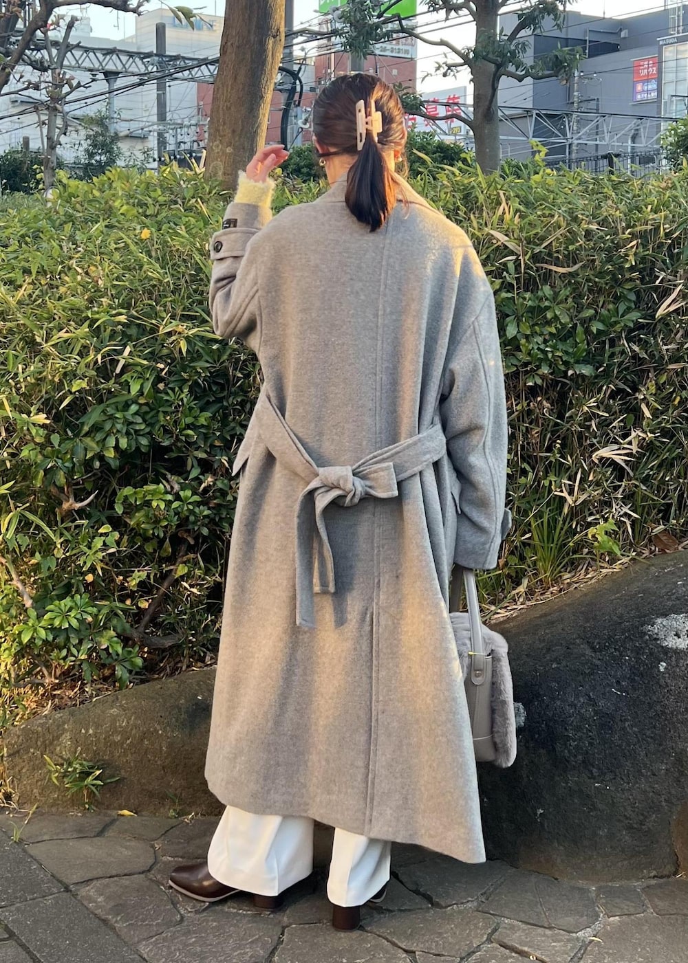 ベージュ系のチェスターコート、ブラウン系のショルダーバッグ、イエロー系のニット/セーターを着用したレディースの秋コーディネートの3枚目の写真