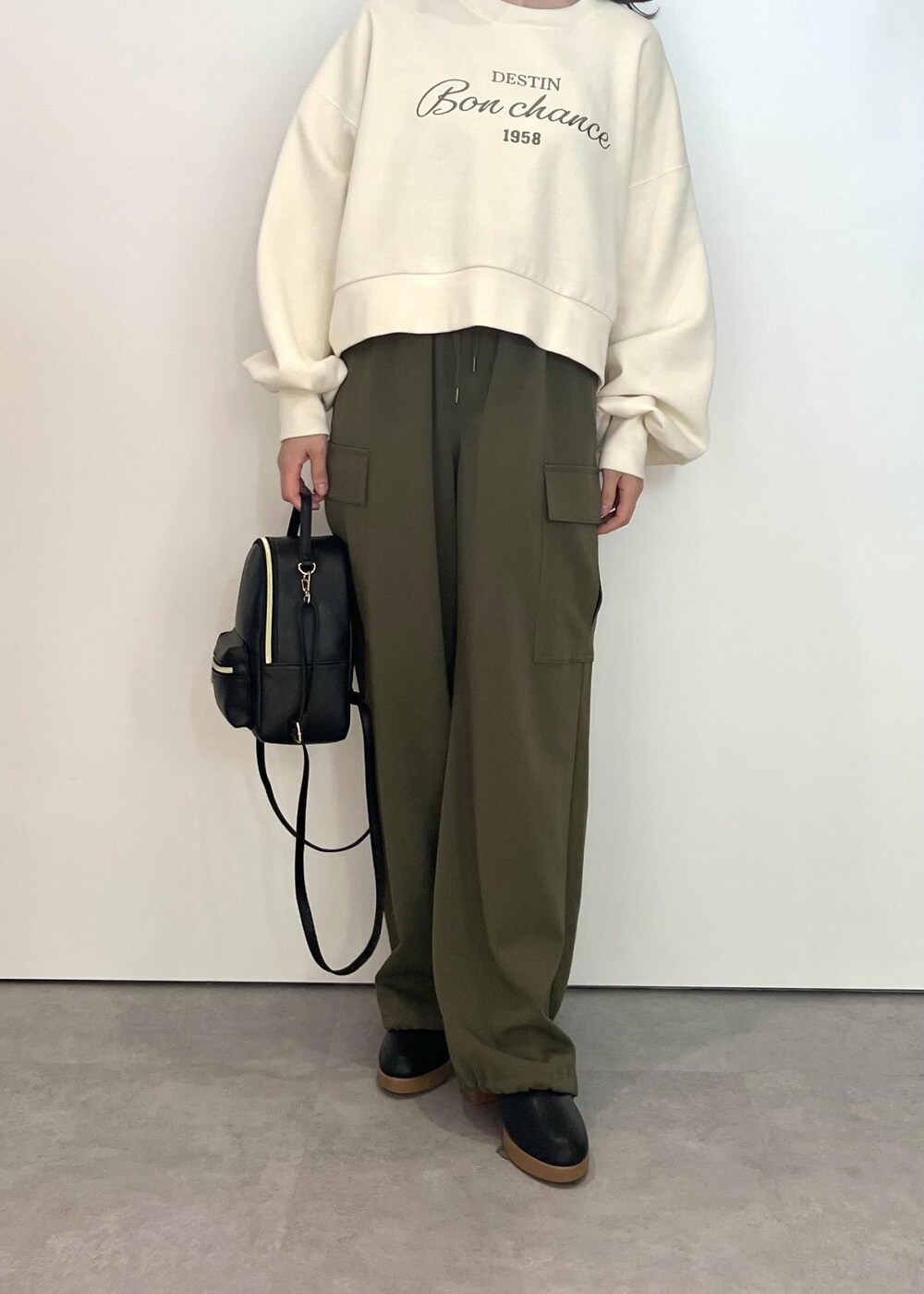 ブラック系のバックパック/リュック、ブラック系のブーツ、ホワイト系のスウェットを着用したレディースの秋コーディネートの4枚目の写真