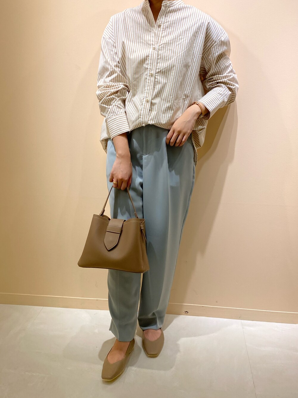 ブラウン系のショルダーバッグ、ブラウン系のパンプス、ベージュ系のシャツ/ブラウスを着用したレディースの春コーディネートの3枚目の写真