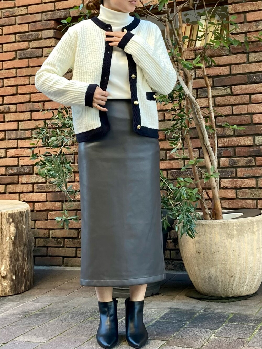 ホワイト系のカーディガン/ボレロ、グレー系のスカート、ブラック系のブーツを着用したレディースの冬コーディネートの3枚目の写真