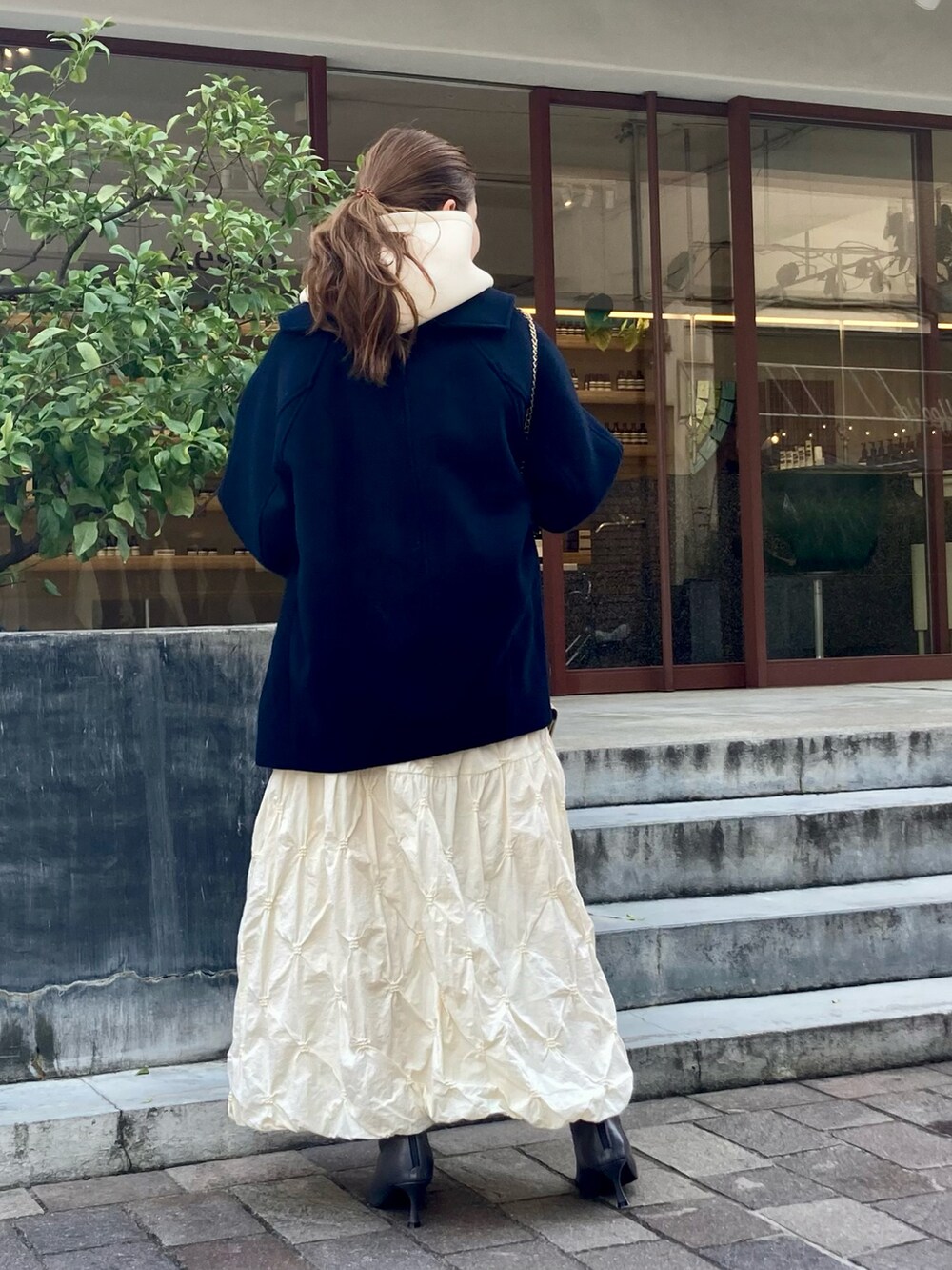 グレー系のブーツ、ゴールド系のハンドバッグ、ホワイト系のTシャツ/カットソーを着用したレディースの秋コーディネートの3枚目の写真