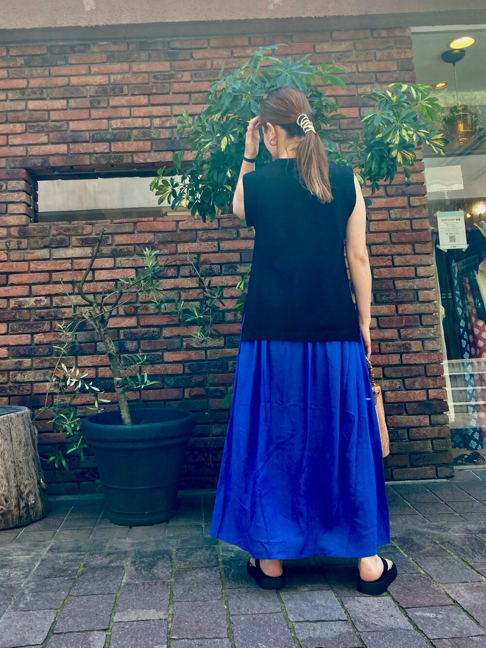 ブラック系のニット/セーター、ブルー系のスカート、ブラウン系のハンドバッグを着用したレディースの春コーディネートの2枚目の写真