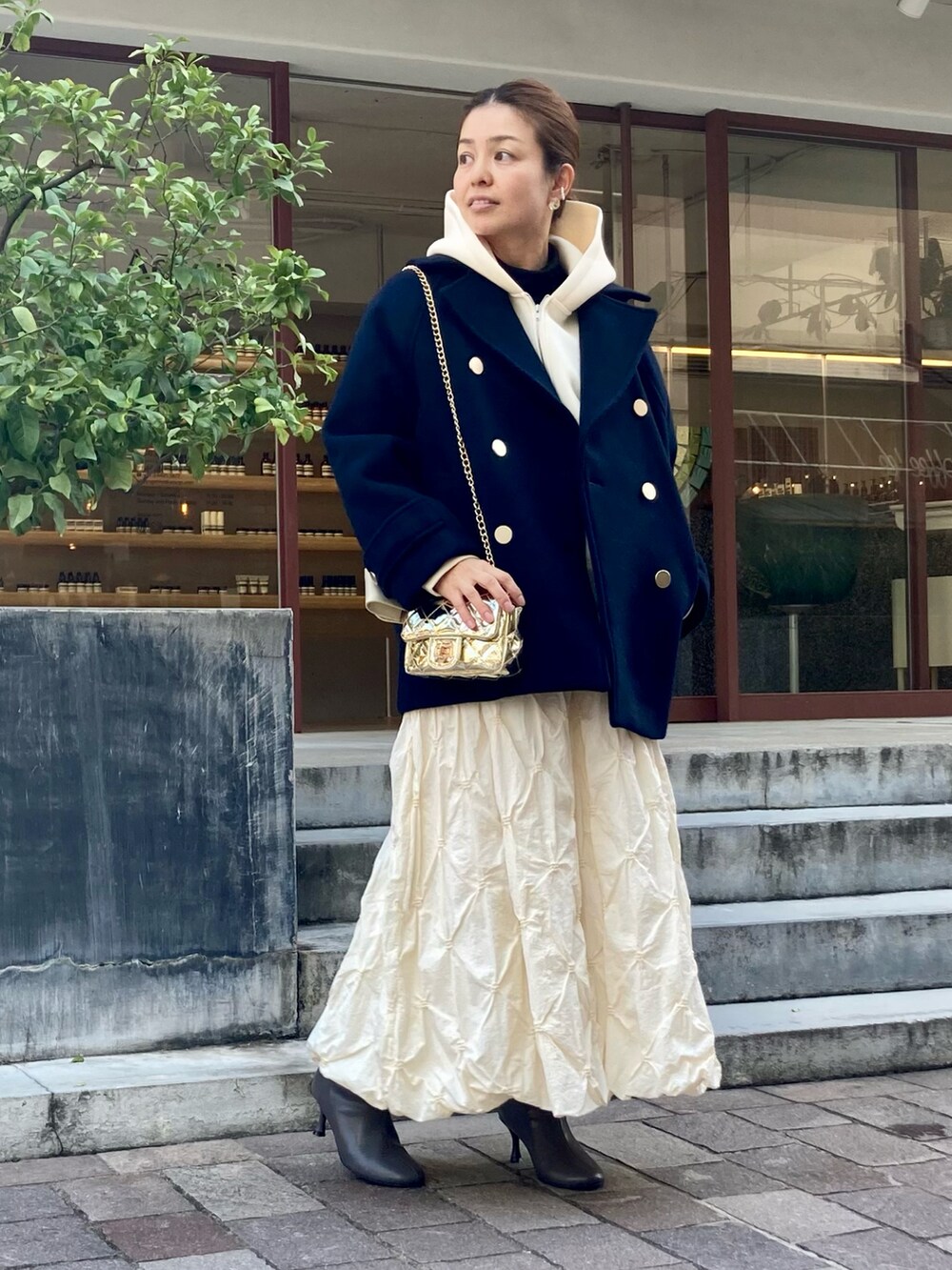 グレー系のブーツ、ゴールド系のハンドバッグ、ホワイト系のTシャツ/カットソーを着用したレディースの秋コーディネートの2枚目の写真