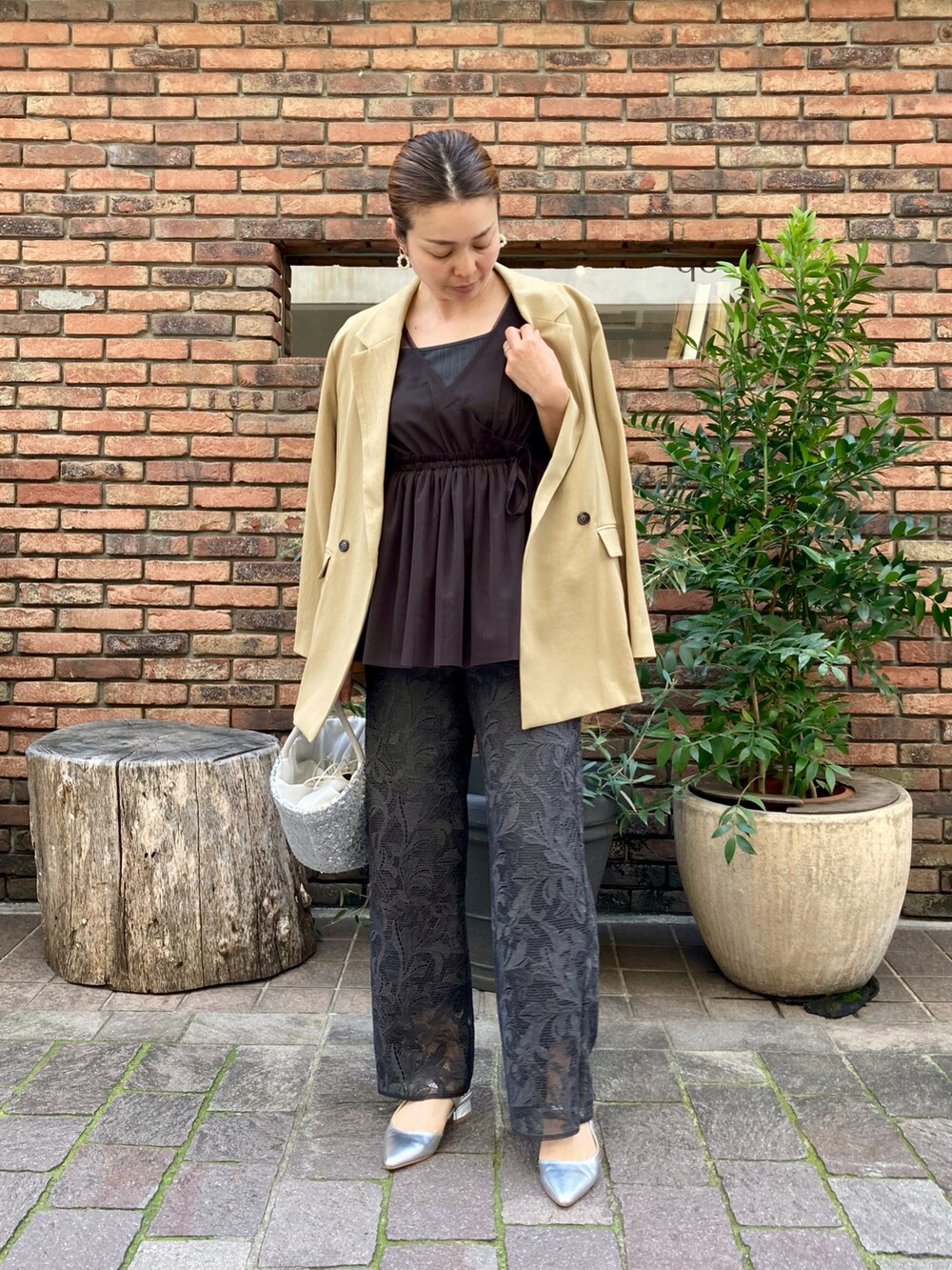 シルバー系のハンドバッグ、グレー系のシャツ/ブラウス、ブラウン系のノーカラージャケットを着用したレディースの春コーディネートの2枚目の写真