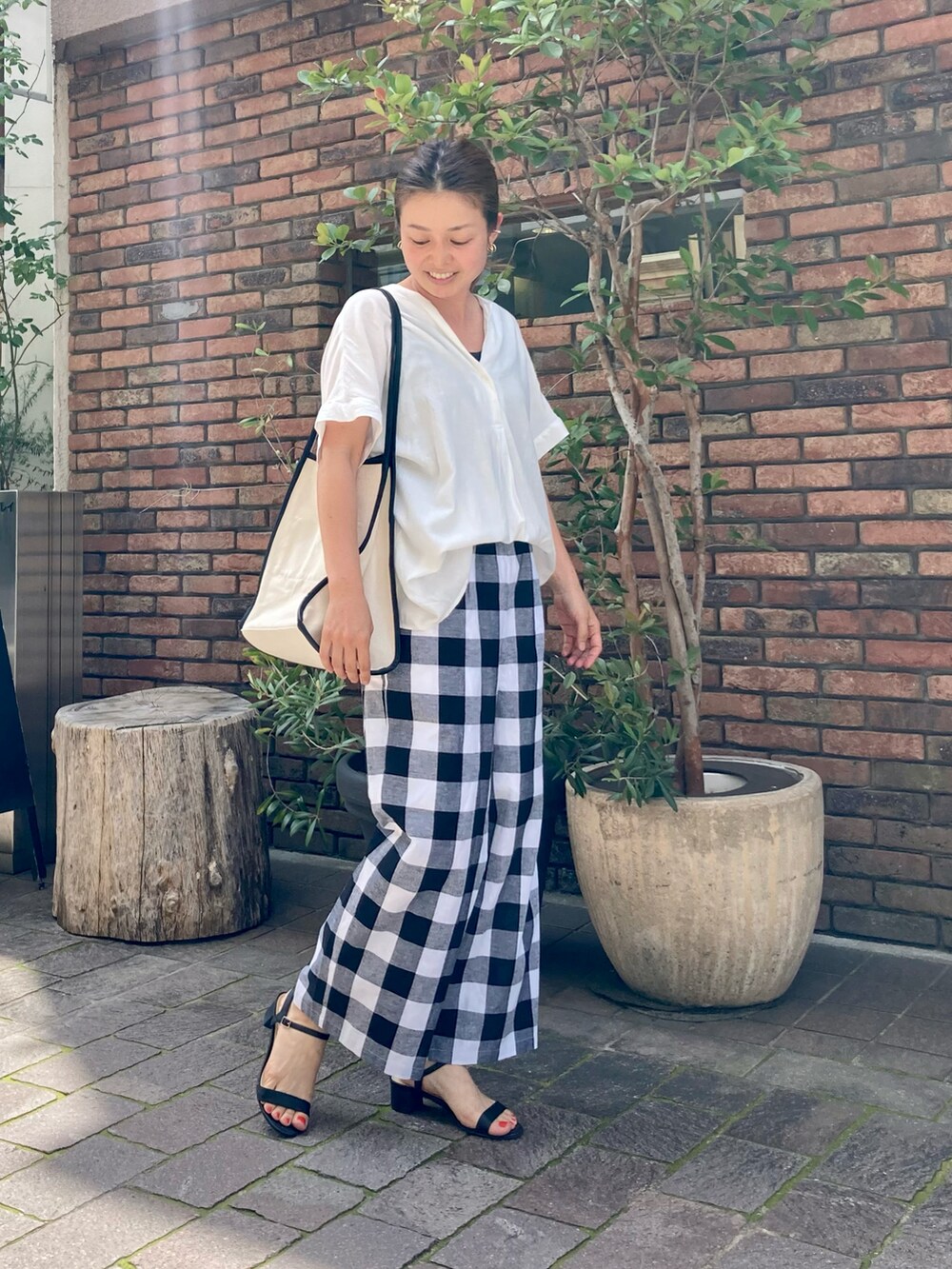 ホワイト系のシャツ/ブラウス、ホワイト系のトートバッグ、ブラック系のサンダルを着用したレディースの夏コーディネートの2枚目の写真