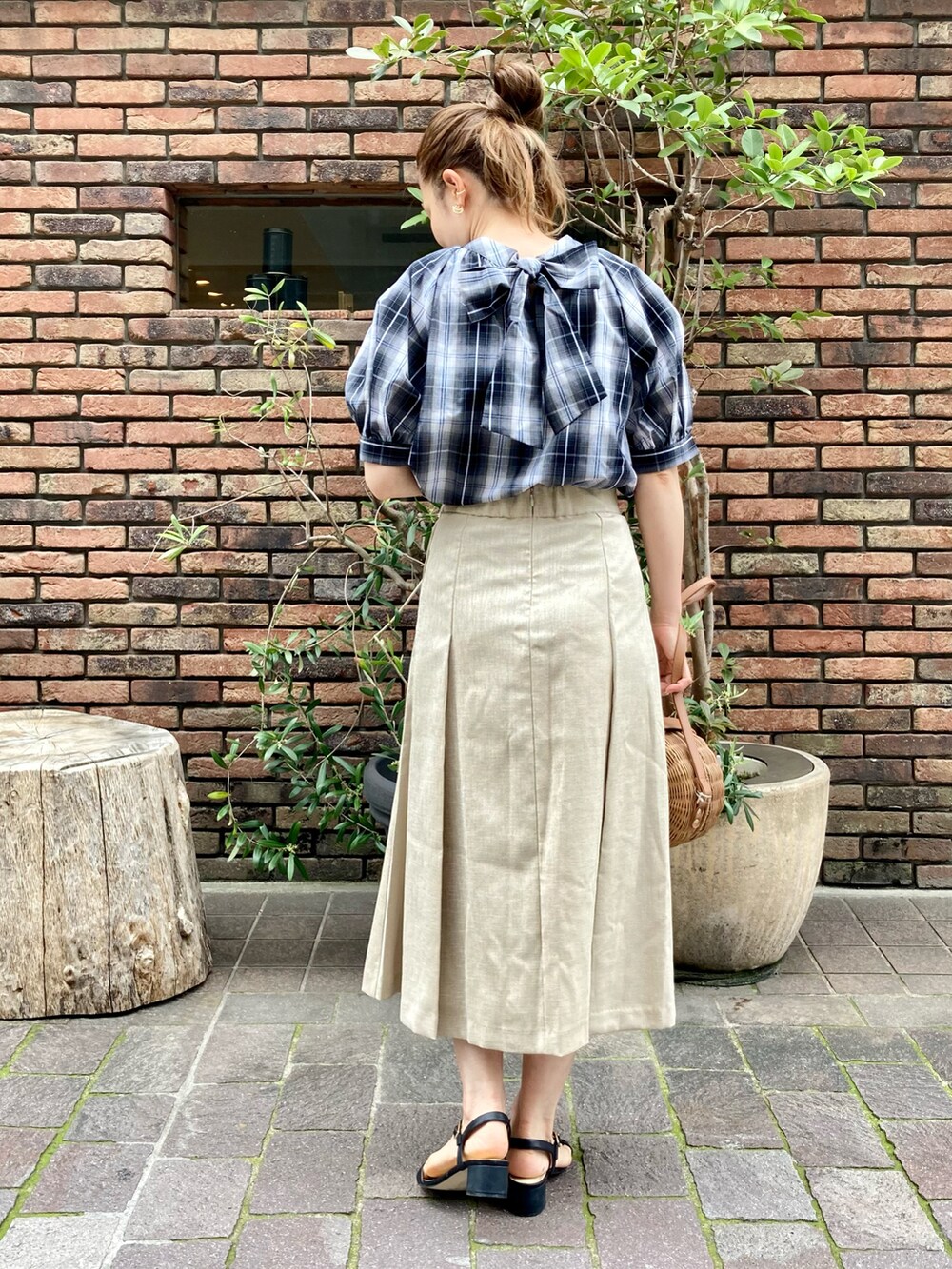 ブラック系のシャツ/ブラウス、ベージュ系のスカート、ブラック系のサンダルを着用したレディースの春コーディネートの2枚目の写真