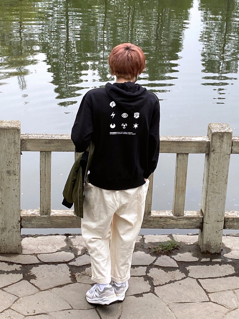 グリーン系のブルゾン、ブラック系のパーカー、ホワイト系のその他パンツを着用したメンズの春コーディネートの2枚目の写真