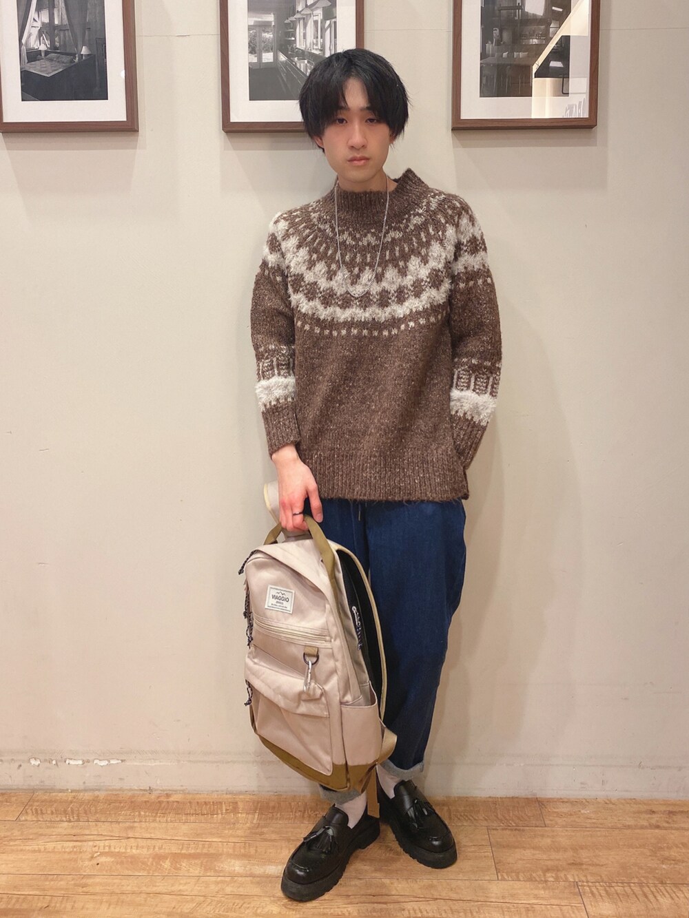 イエロー系のニット/セーター、ブルー系のデニムパンツ、ベージュ系のバックパック/リュックを着用したメンズの冬コーディネートの2枚目の写真