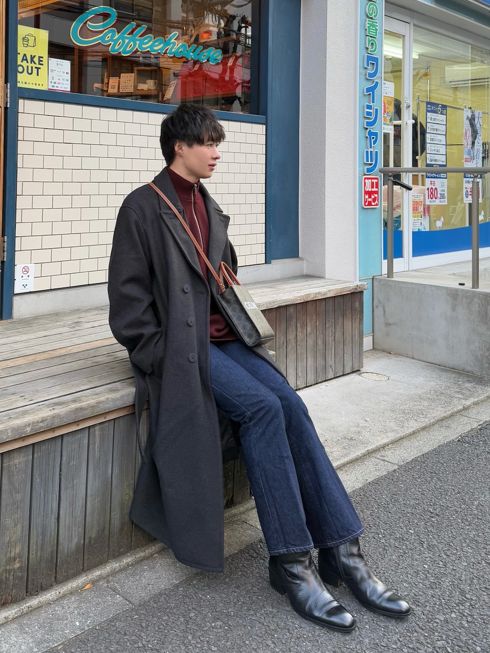 グレー系のチェスターコート、レッド系のニット/セーター、ブルー系のデニムパンツを着用したメンズの冬コーディネートの2枚目の写真