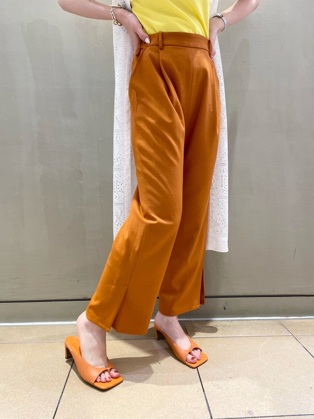 オレンジ系のパンツ、イエロー系のTシャツ/カットソー、ホワイト系のワンピースを着用したレディースの春コーディネートの3枚目の写真