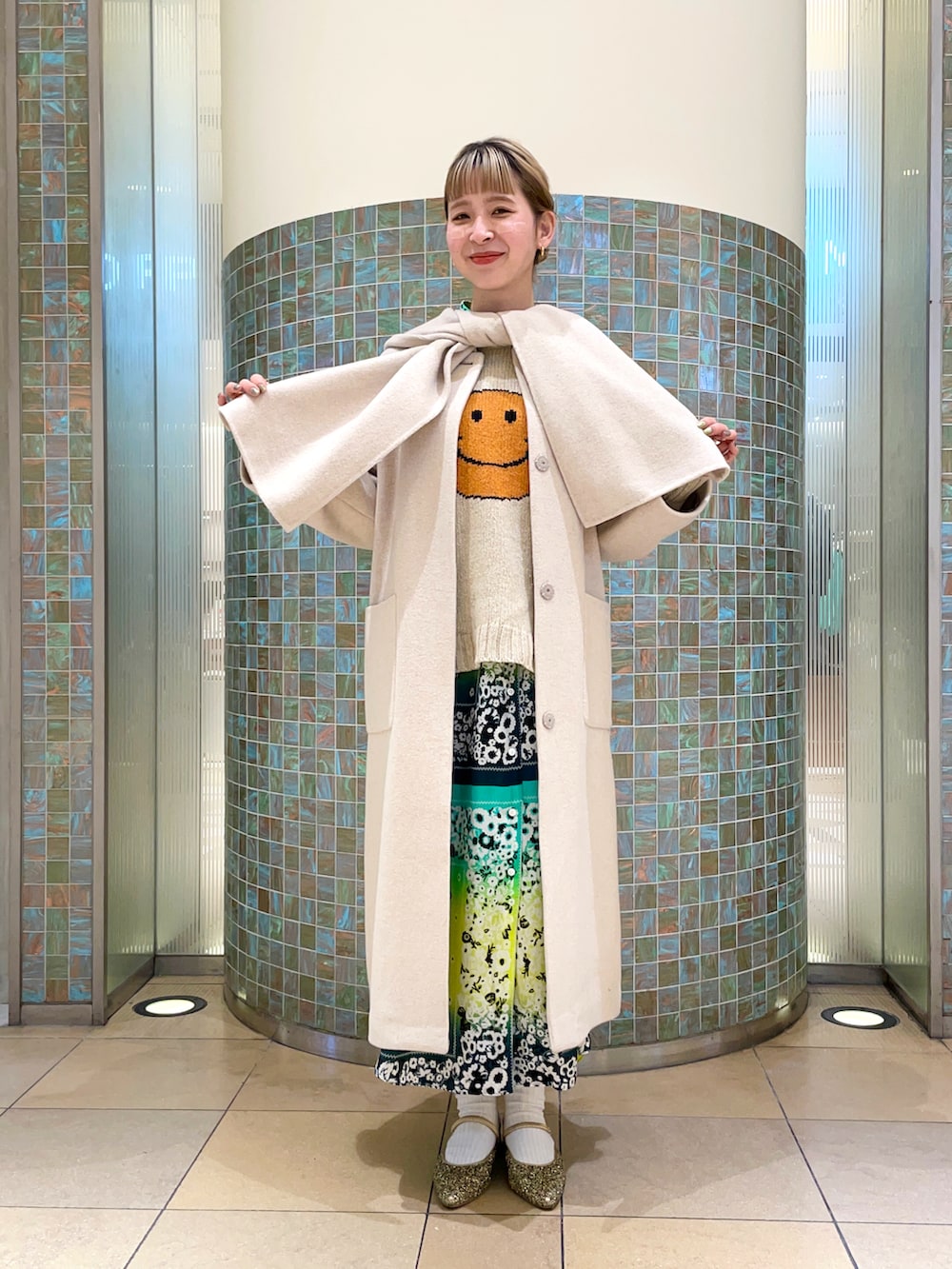 ホワイト系のノーカラーコートを着用したレディースの冬コーディネートの2枚目の写真