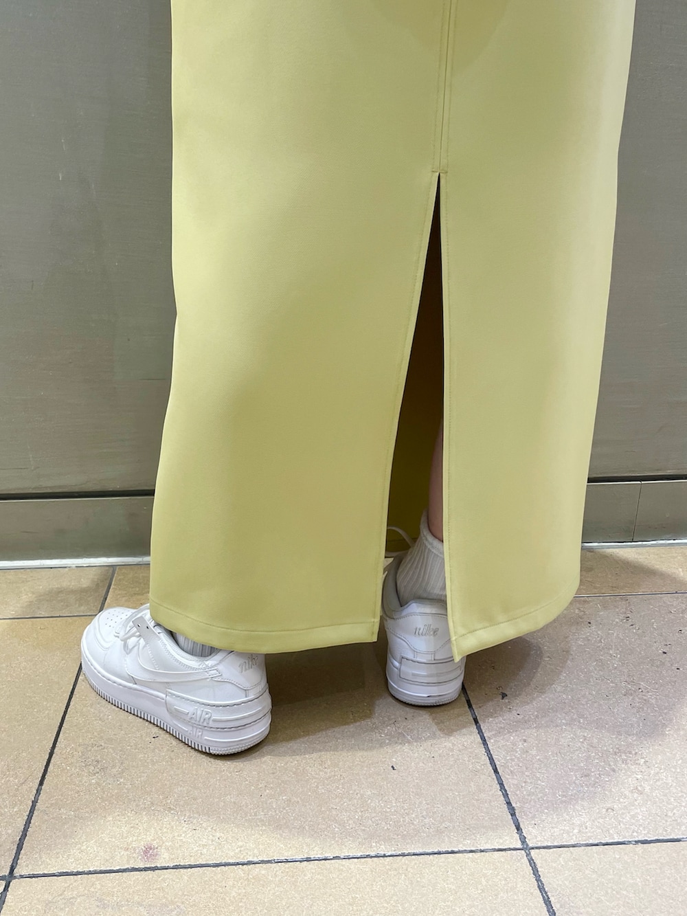 イエロー系のスカート、グリーン系のノーカラーコート、グリーン系のベストを着用したレディースの秋コーディネートの5枚目の写真