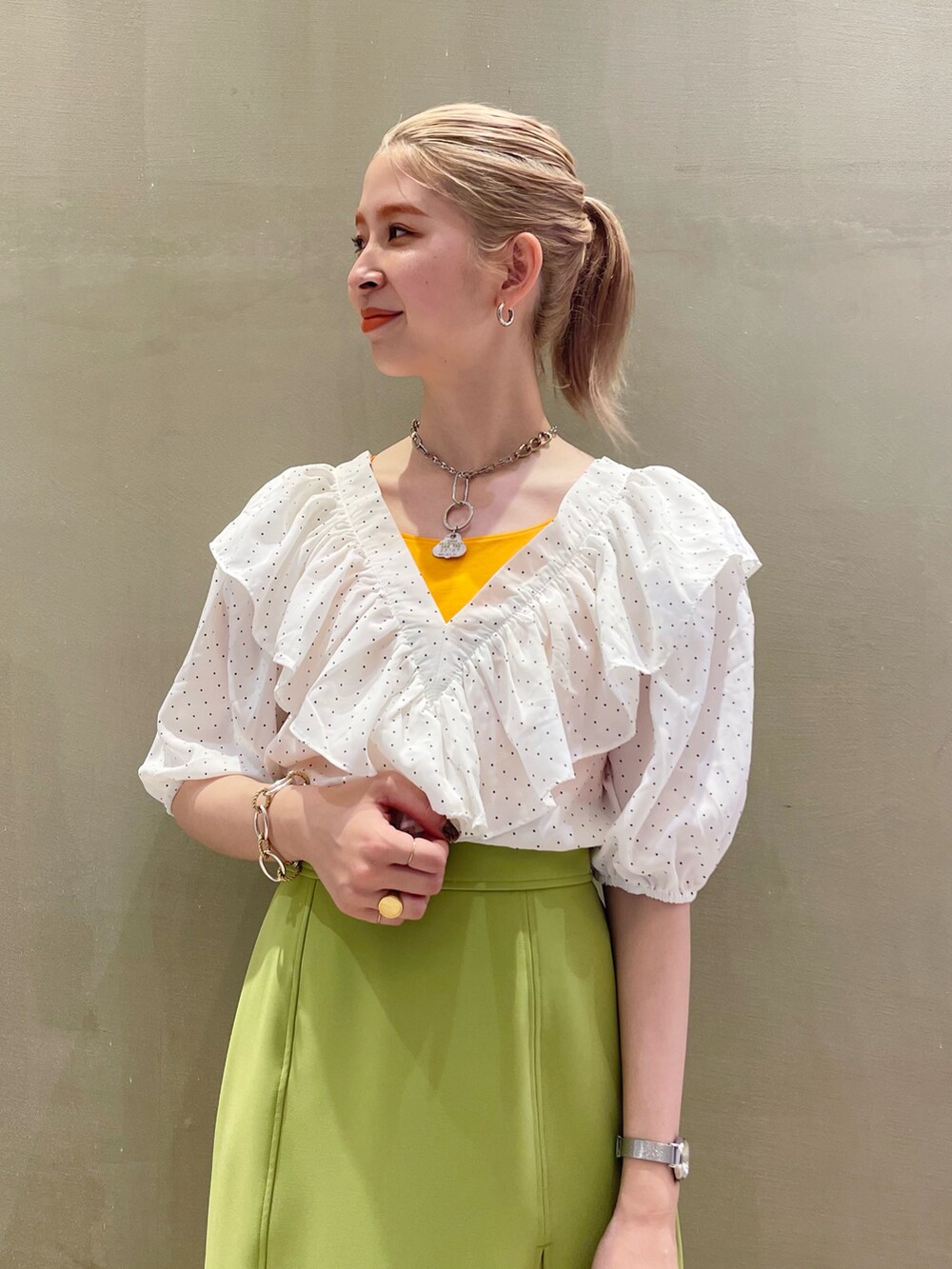 グリーン系のスカート、ホワイト系のシャツ/ブラウス、オレンジ系のキャミソールを着用したレディースの夏コーディネートの3枚目の写真