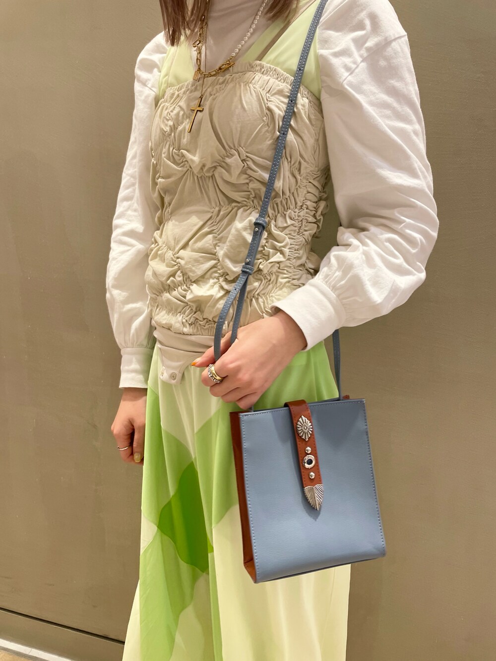 ホワイト系のトップス、ブルー系のショルダーバッグを着用したレディースの冬コーディネートの4枚目の写真