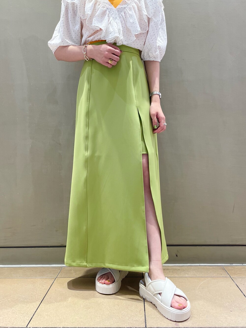 グリーン系のスカート、ホワイト系のシャツ/ブラウス、オレンジ系のキャミソールを着用したレディースの夏コーディネートの4枚目の写真