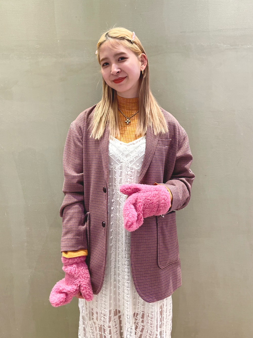 ピンク系のテーラードジャケット、オレンジ系のニット/セーター、ピンク系の手袋を着用したレディースの秋コーディネートの2枚目の写真