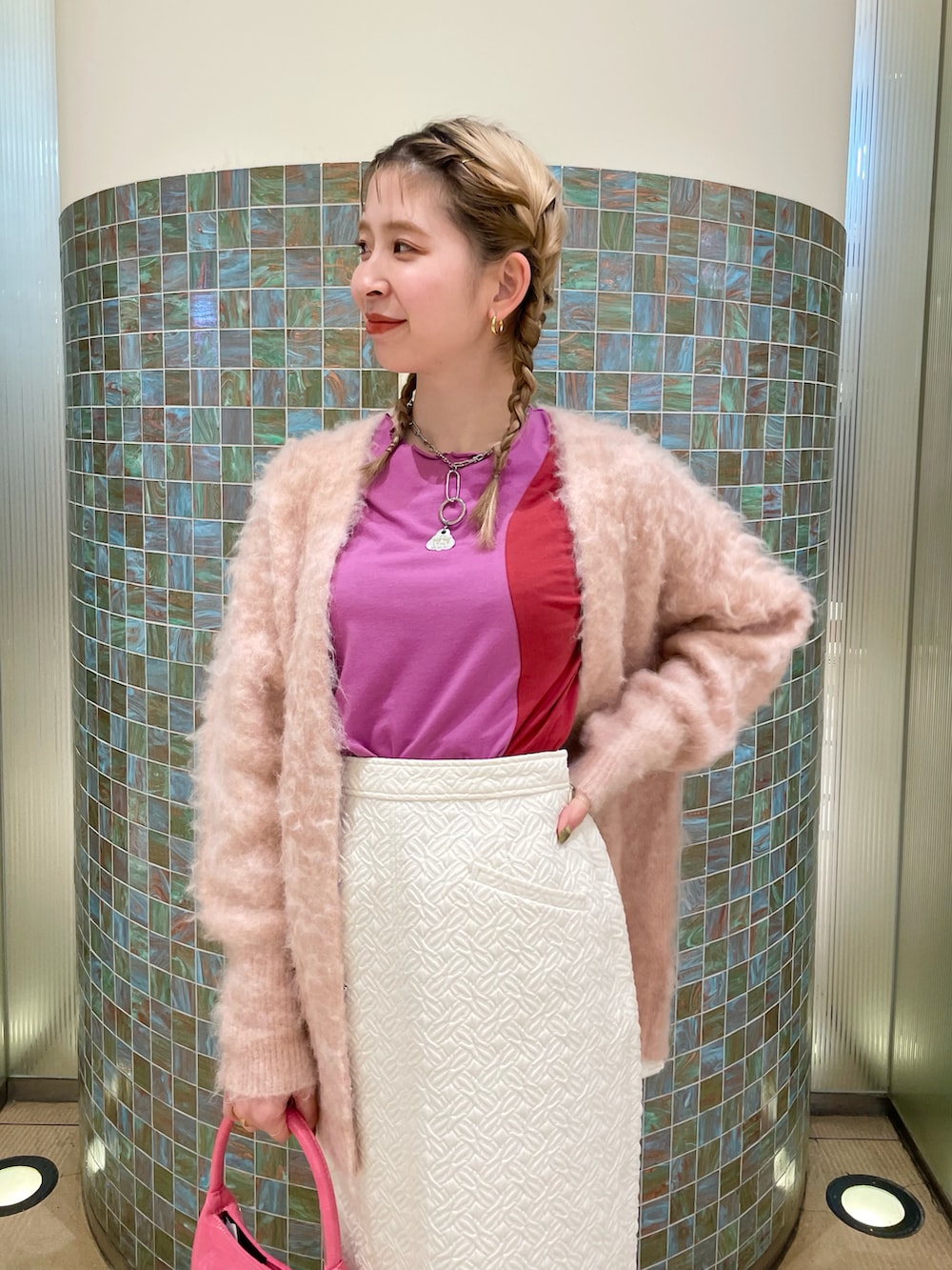 ピンク系のカーディガン/ボレロ、ピンク系のTシャツ/カットソー、ホワイト系のスカートを着用したレディースの冬コーディネートの3枚目の写真